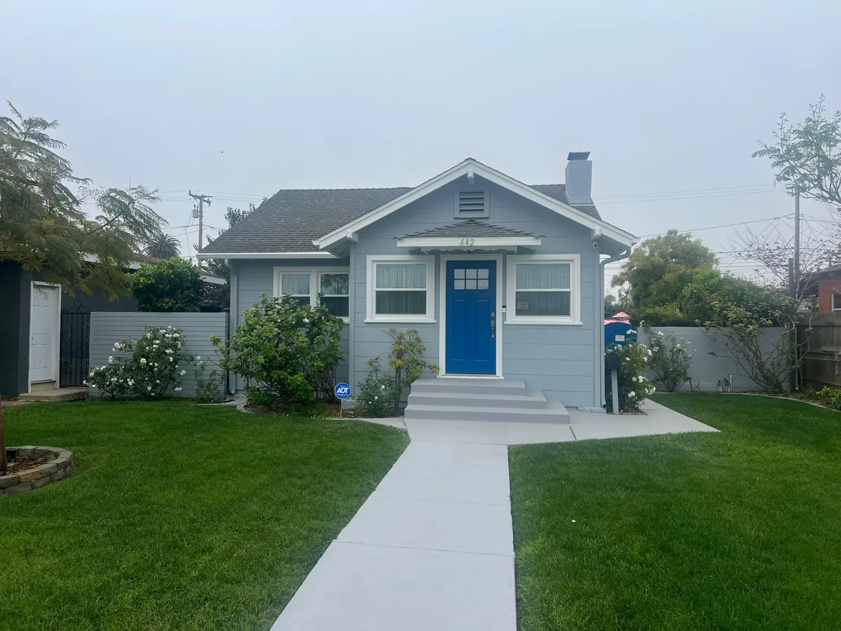 Craftsman bungalow exterior repainted light blue-gray with a new blue front door — after