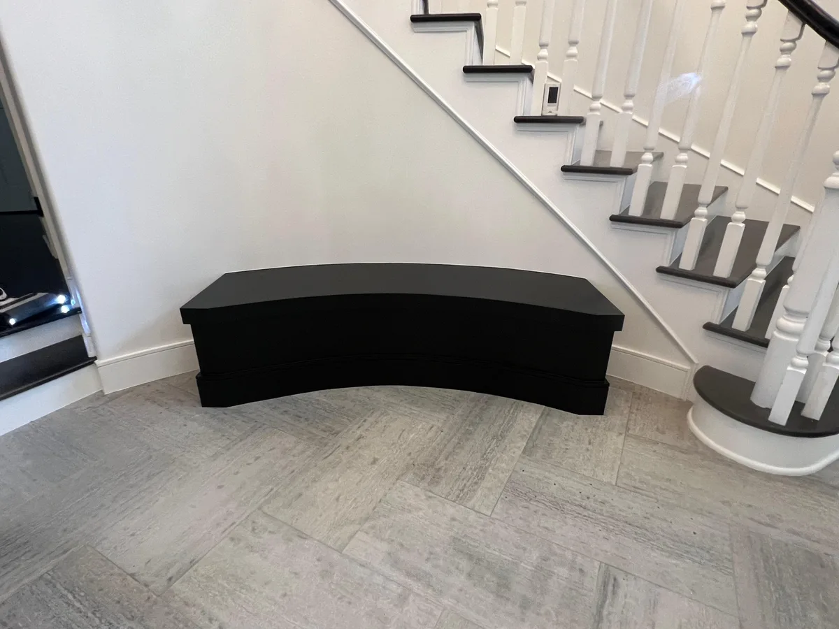 Curved built-in entry bench painted glossy black to match the staircase — after
