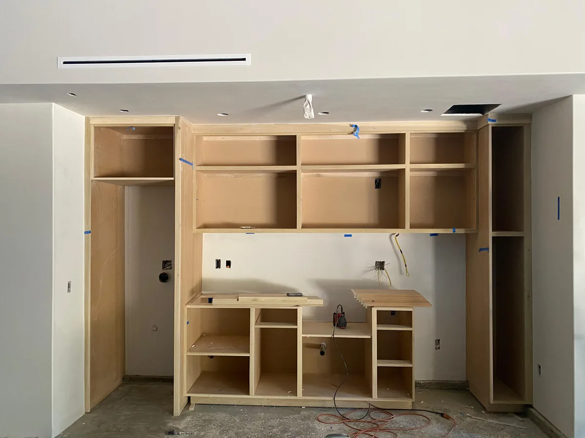Bare wood kitchenette cabinetry finished in bold red and gray — before