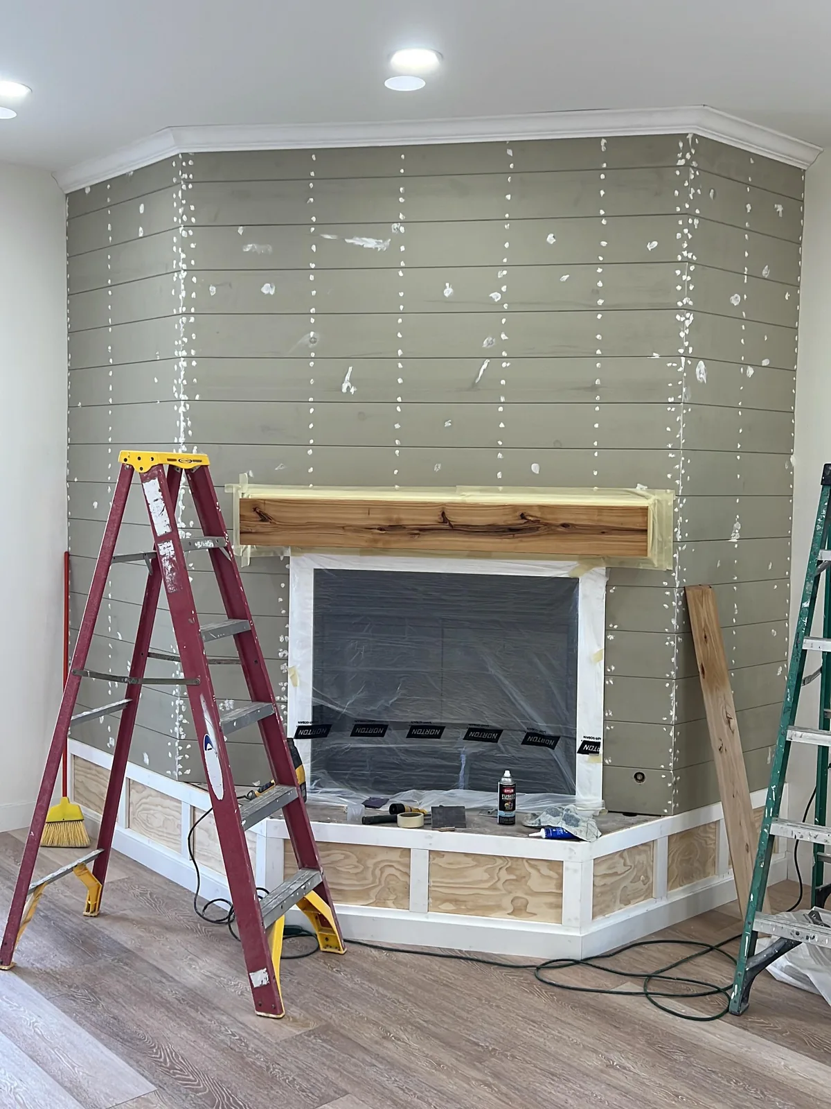 Shiplap fireplace accent wall repainted crisp white with a natural wood mantel — before