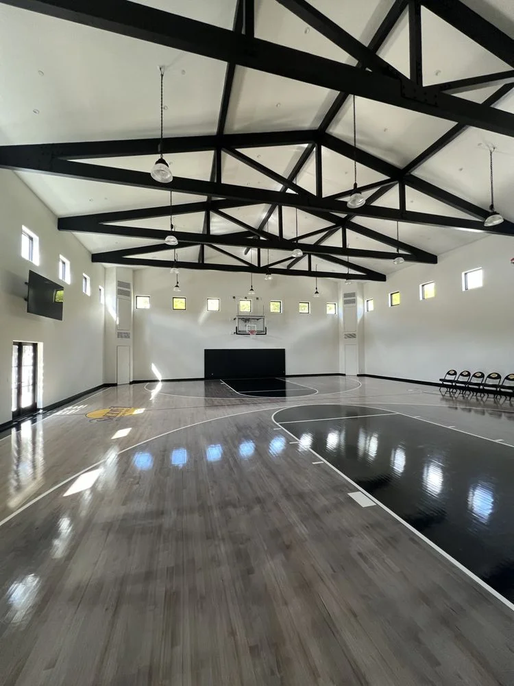Custom home basketball court with vaulted ceiling and exposed black steel trusses