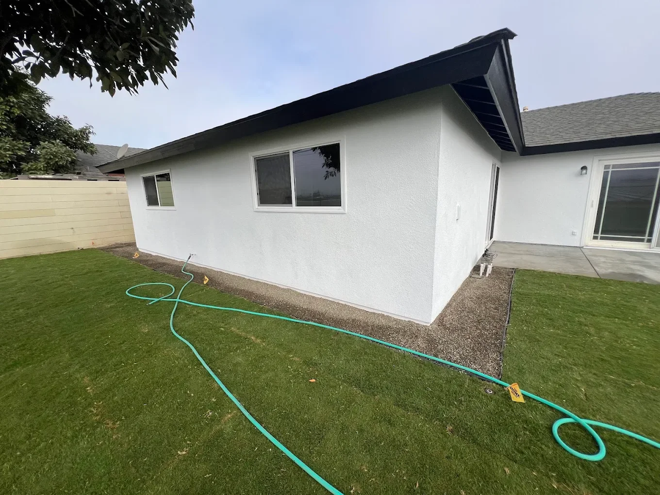 Close-up of a white stucco house corner with crisp black roofline trim
