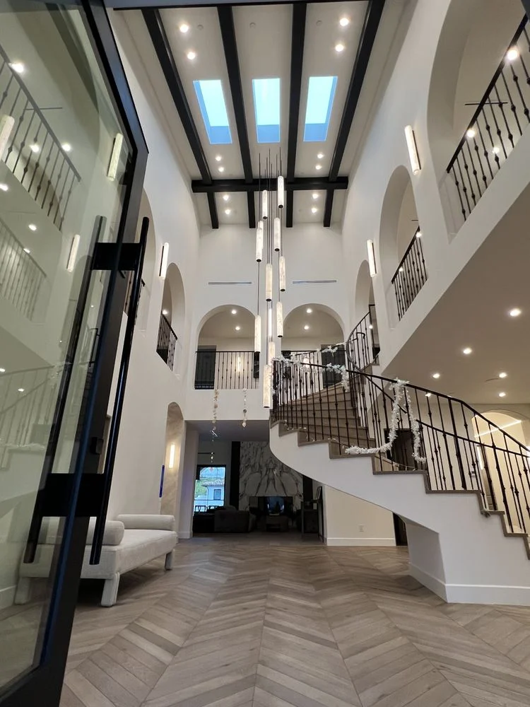 Grand foyer with curved staircase, wrought iron rail, and arched barrel-vault hallway
