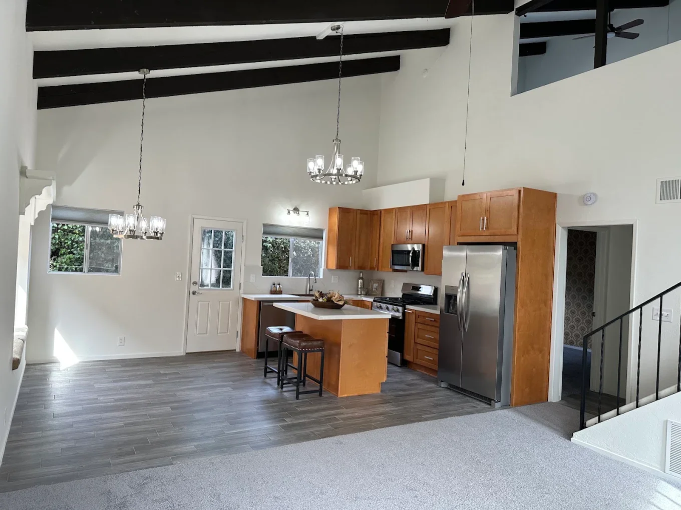 Kitchen with vaulted ceiling, black exposed beams, and wood cabinets