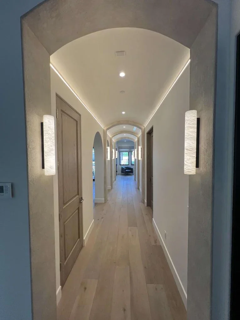 Arched hallway with wood door and wall sconces