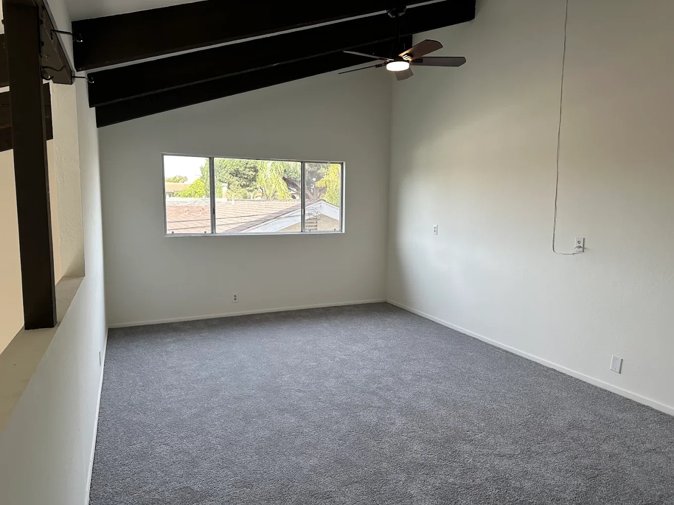 Room with a single black ceiling beam and ceiling fan