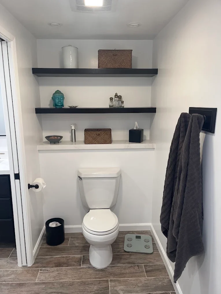 Powder room with floating black shelves and white walls