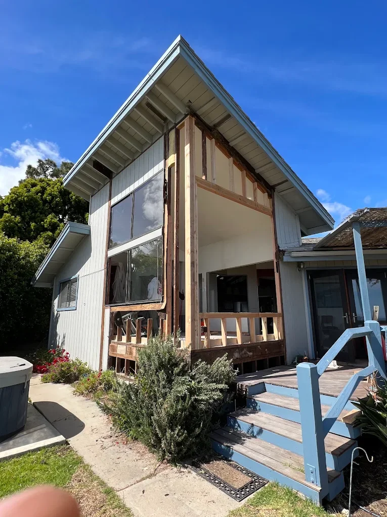 House exterior mid-remodel with new trim and deck stairs