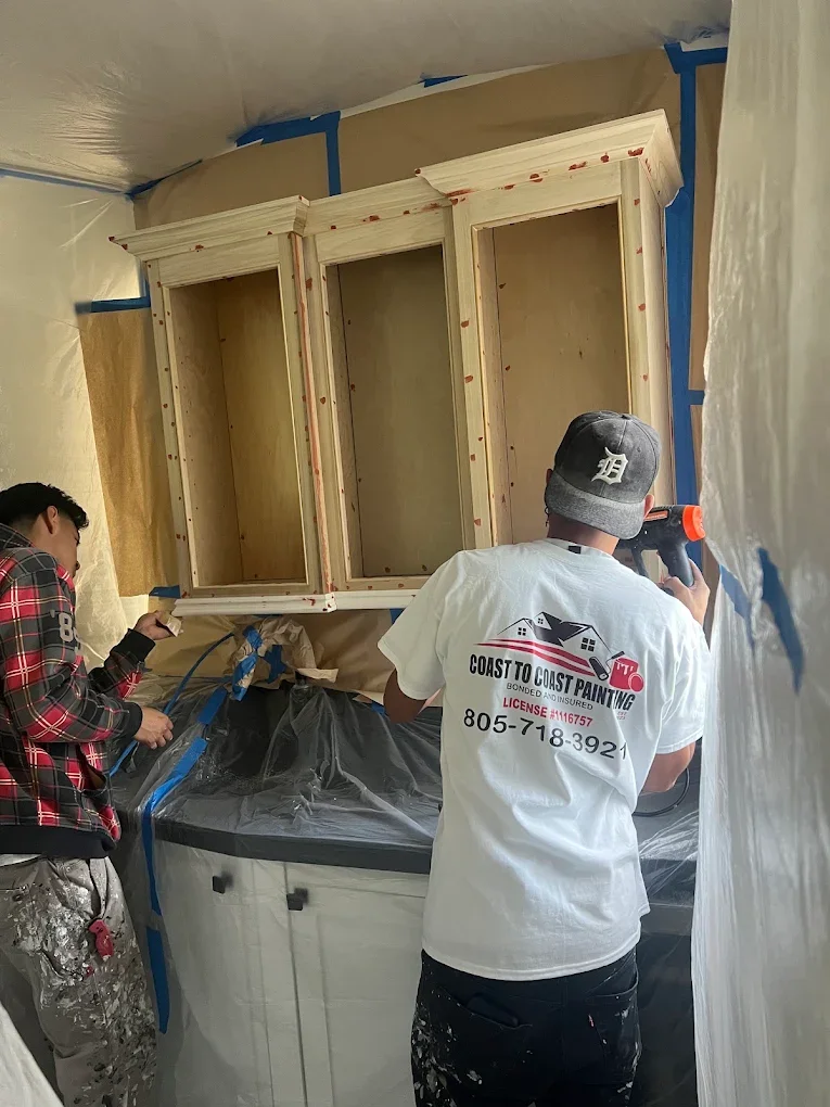 Crew spray-painting a built-in cabinet hutch cream