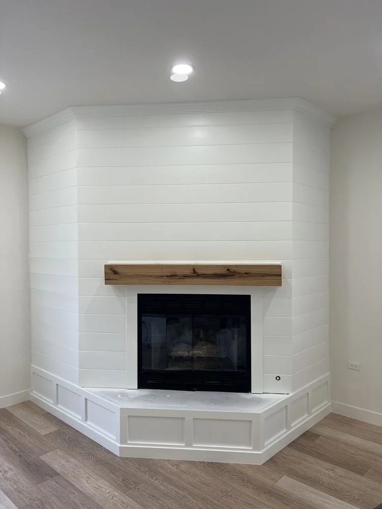 Freshly painted white shiplap fireplace wall with wood mantel
